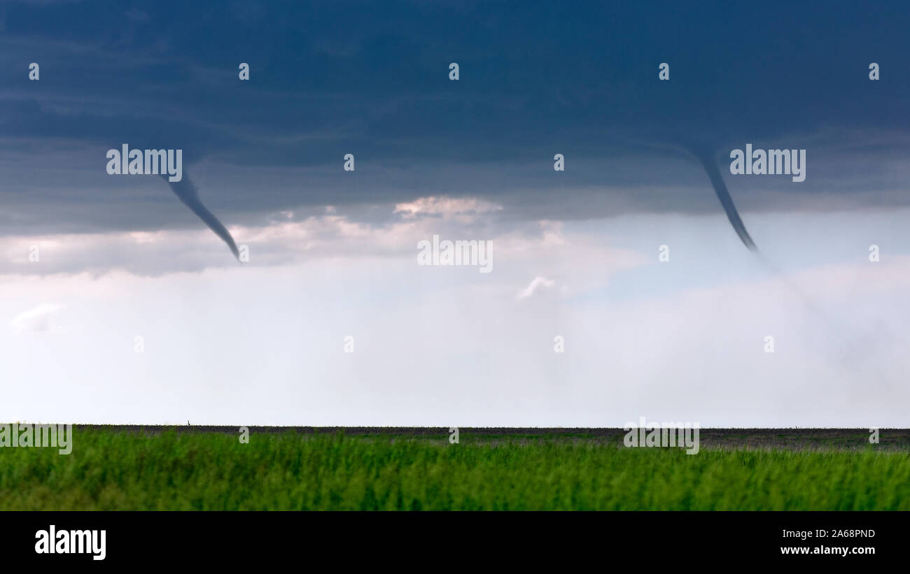 Las nubes embudo gemelas aparecen en un campo como un par de tornados landspout se desarrollan a partir de una tormenta, cerca de San Francisco, Kansas, Estados Unidos. Foto de stock