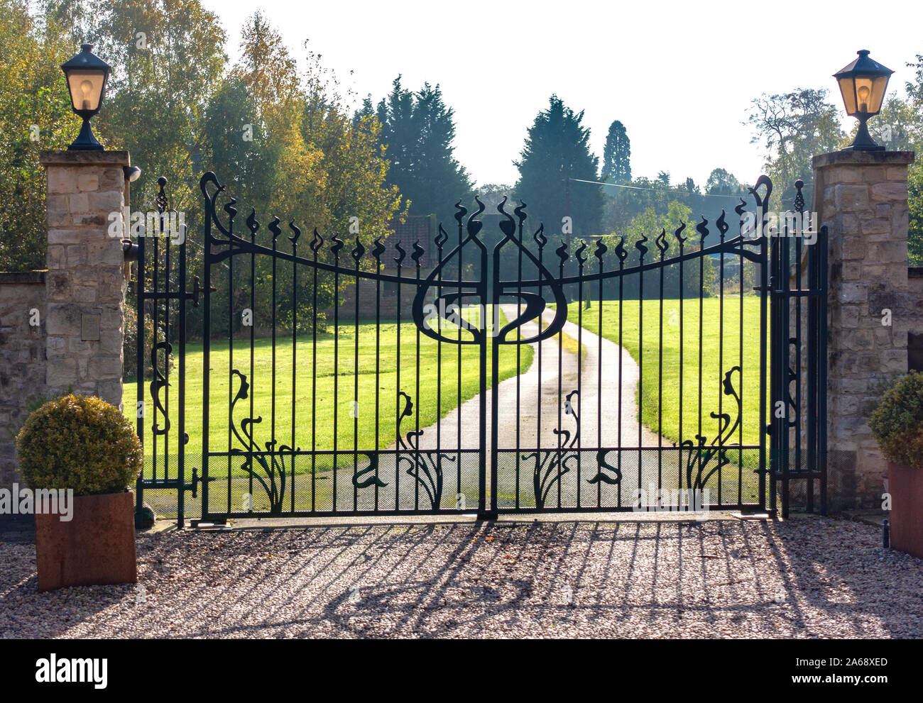 Puertas de seguridad de metal. 2 grandes puertas de jardín ornamental de  hierro forjado y largo camino de entrada Fotografía de stock - Alamy