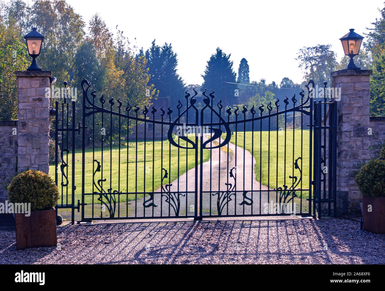 Puertas de seguridad de metal. 2 grandes puertas de jardín ornamental de  hierro forjado y largo camino de entrada Fotografía de stock - Alamy
