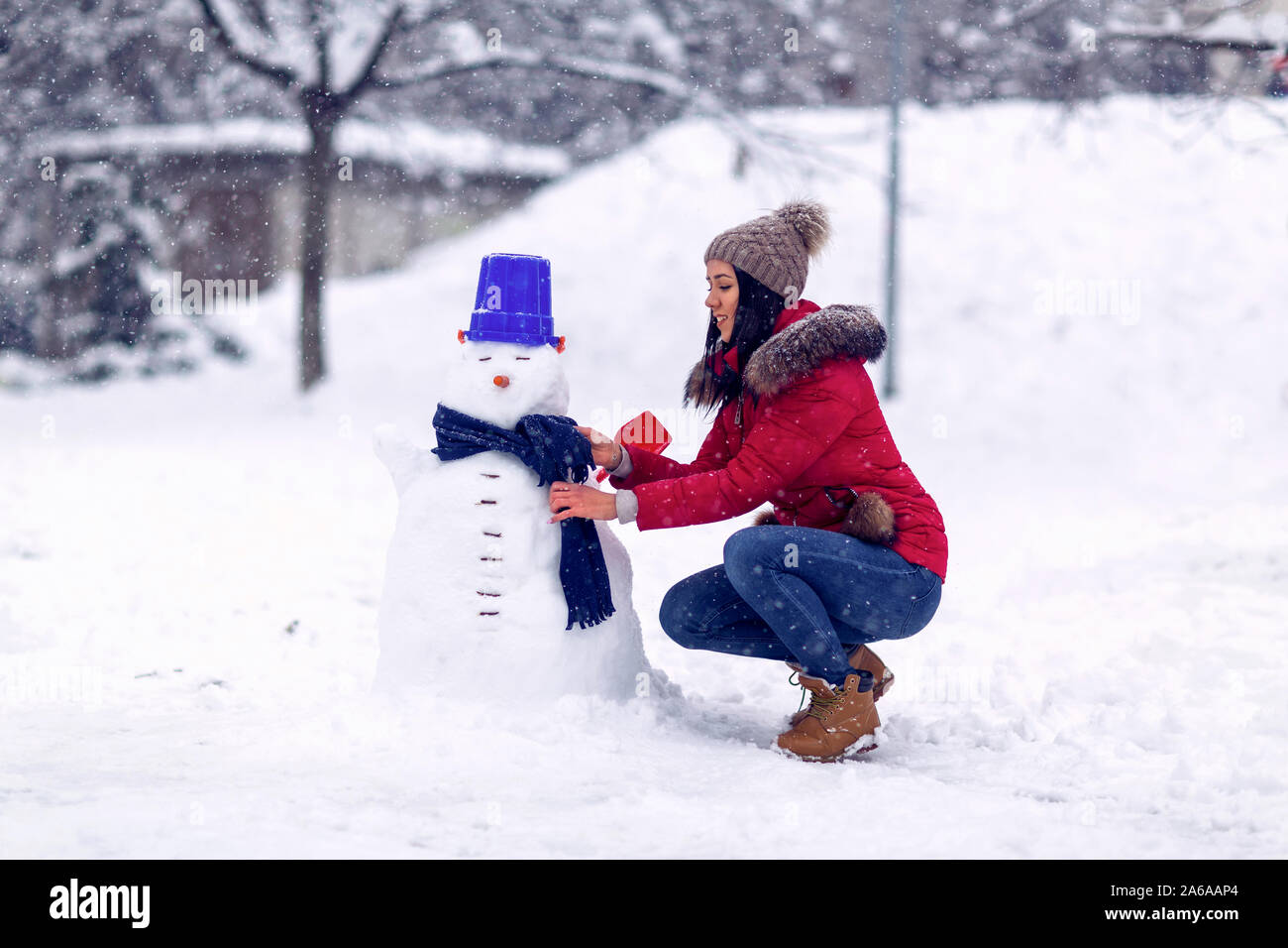 Mujer feliz jugando con un muñeco de nieve en invierno.día de invierno. Felices fiestas. Foto de stock
