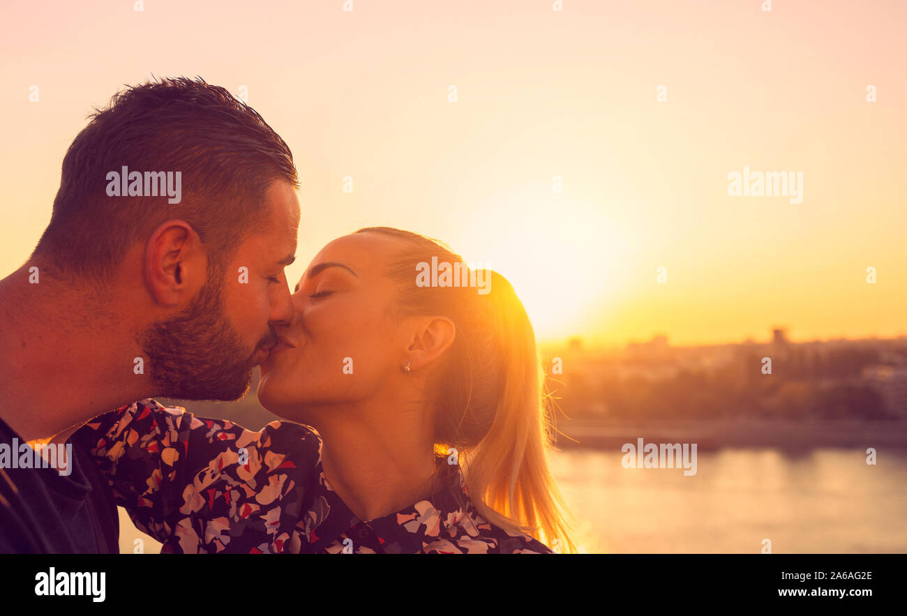 Pareja joven en amor besar en Sunset Foto de stock
