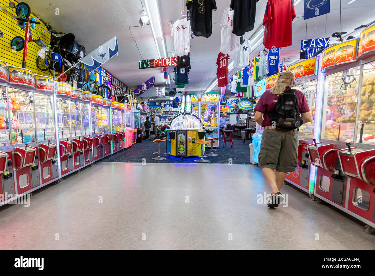 Pocas personas a pie y visitar tiendas y salas de juegos en un paseo vacío en la noche cuando el verano ha terminado. Foto de stock
