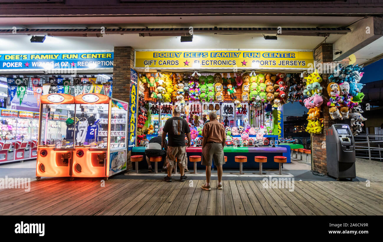 Pocas personas a pie y visitar tiendas y salas de juegos en un paseo vacío en la noche cuando el verano ha terminado. Foto de stock