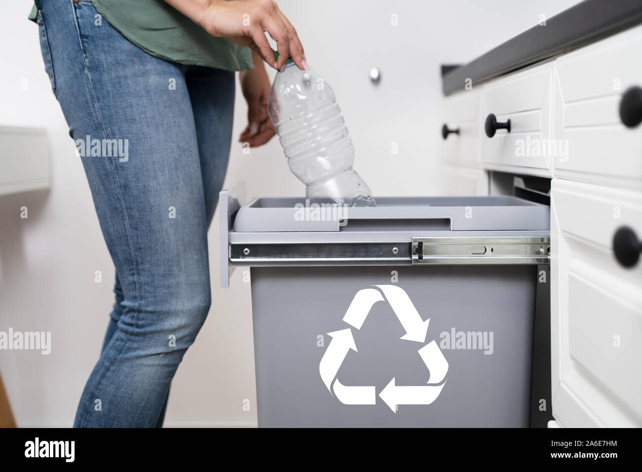 Bajo la sección de la mujer lanzando la botella de plástico vacía en la Papelera de reciclaje en la cocina Foto de stock