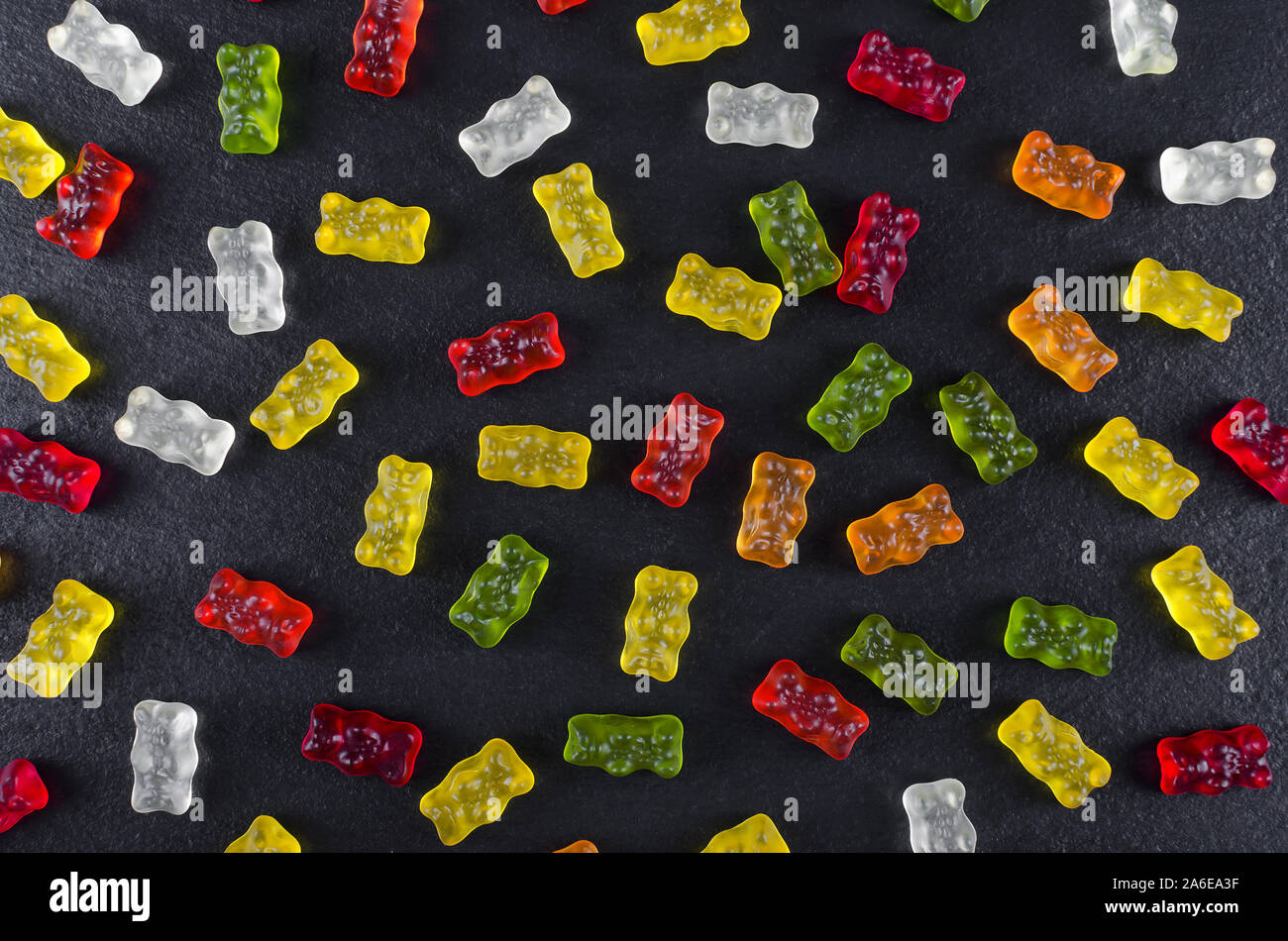 Caramelos de gelatina de colores sobre fondo negro, laicos plana Foto de stock