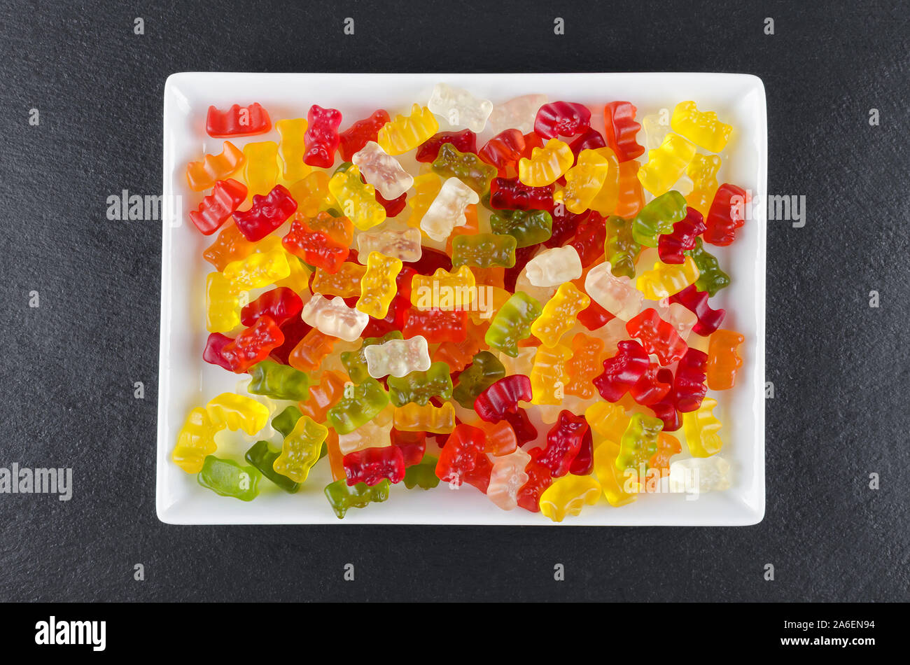Jalea coloridos dulces en una placa blanca sobre fondo negro, vista desde arriba Foto de stock