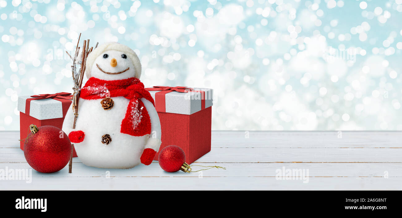 Fondo de navidad con muñeco de nieve, los regalos y las bolas sobre la mesa de madera. Espacio libre junto a texto de felicitación. Foto de stock