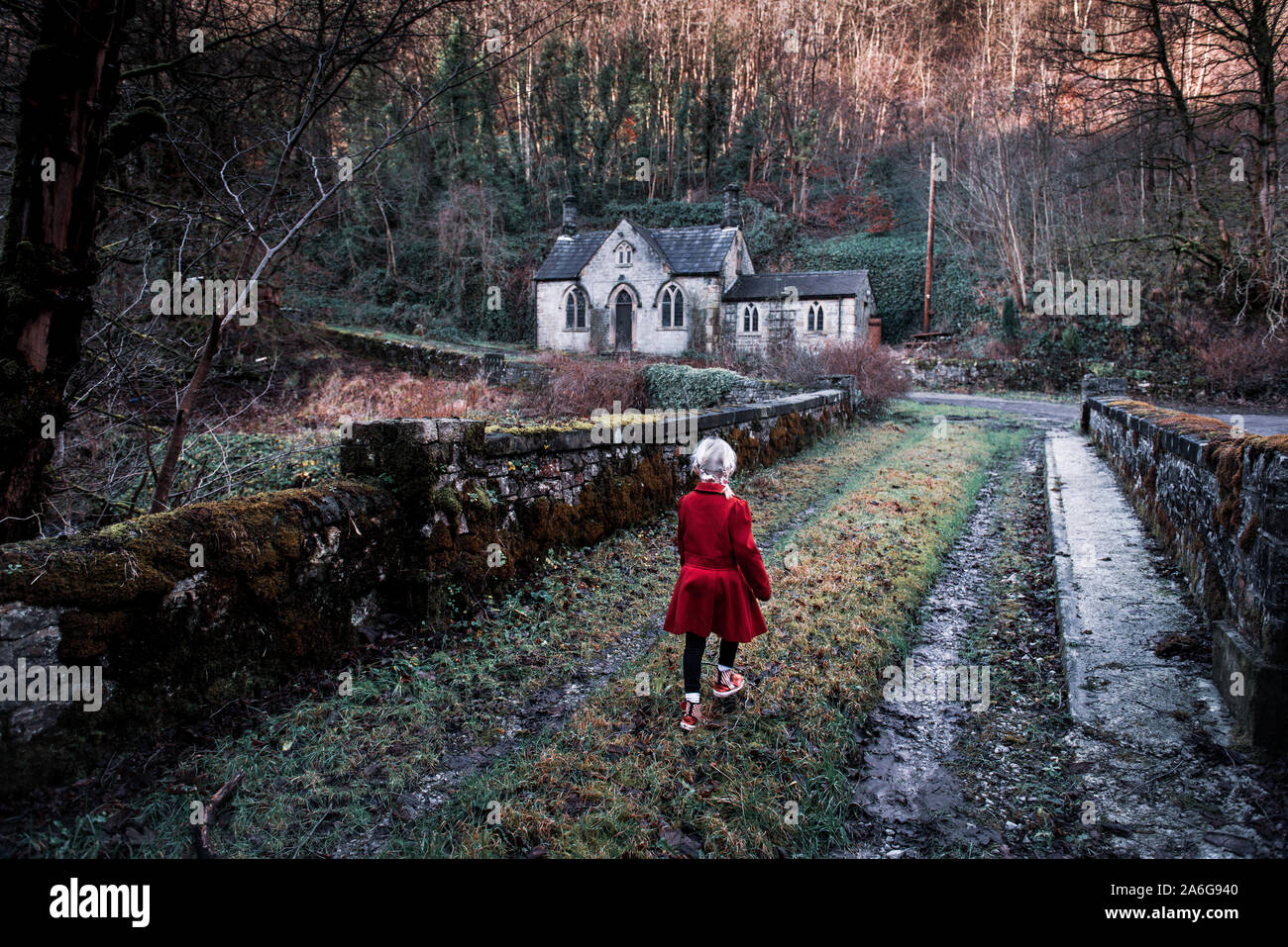Una niña caminando hacia un antiguo miedo, espeluznante casa abandonada, iglesia en el bosque, ubicado en el Derbyshire Peak District National Park, hallow Foto de stock