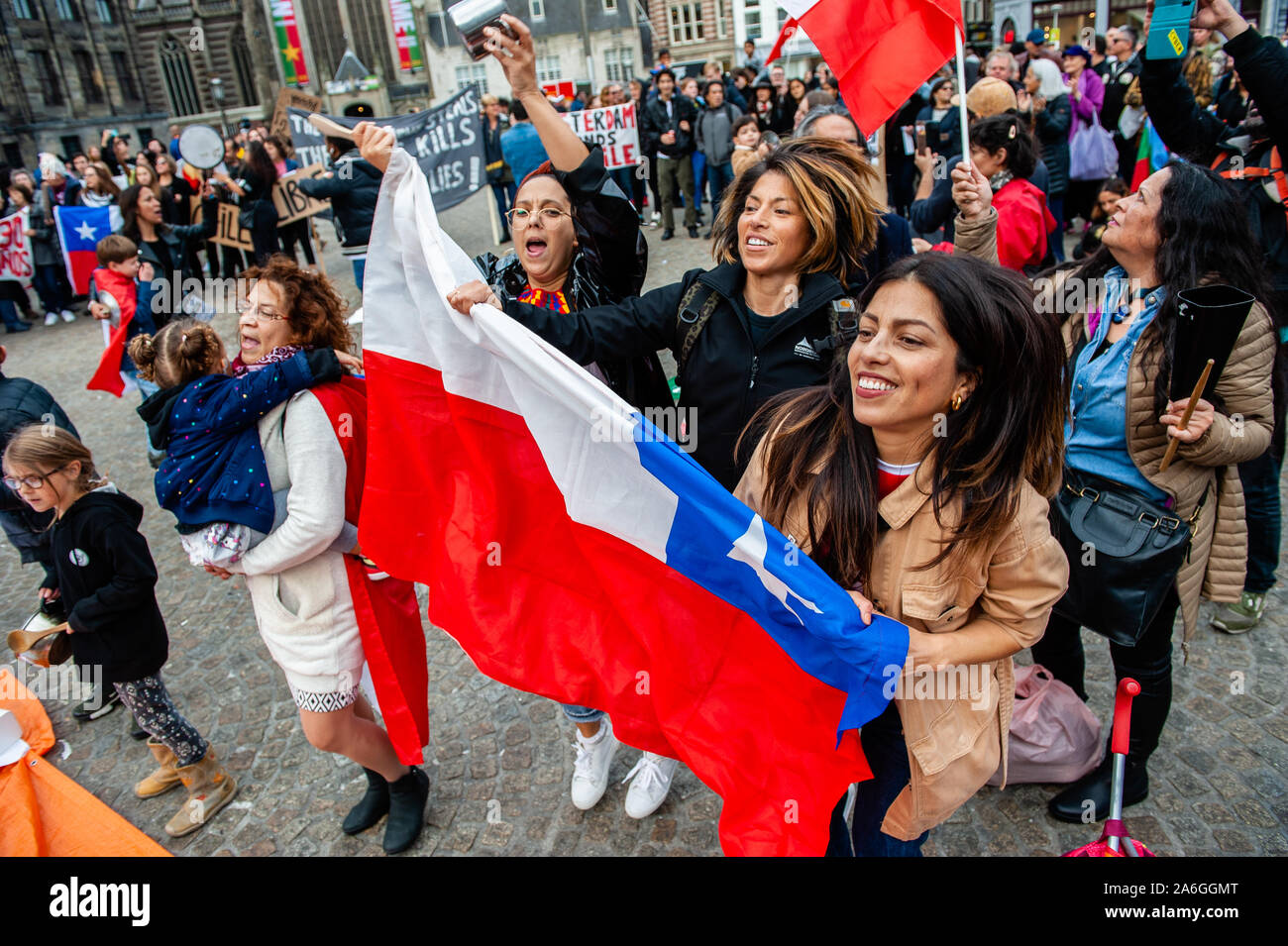 Tres mujeres chilenas se ve saltando sujetando una bandera de Chile durante  la manifestación.La comunidad chilena que vive en los Países Bajos sigue  demostrando para mostrar su descontento con la situación actual