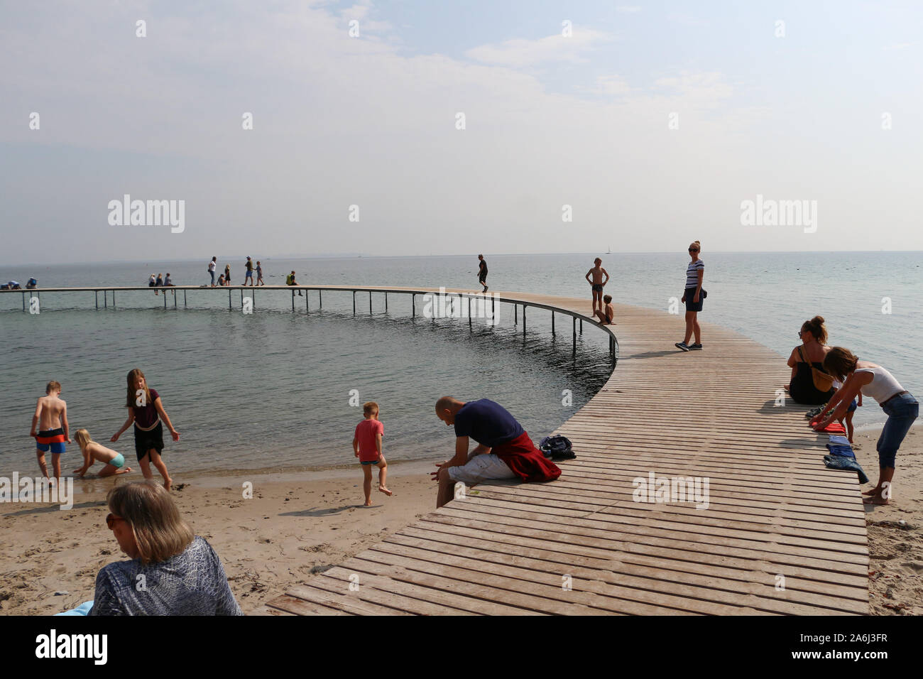 La gente caminando por el puente infinito (Den Uendelige Bro) - muelle de madera con forma de círculo construido sobre un mar de la costa de la Bahía de Aarhus sobre una playa de Varna/Ballehage Playa, creado por el arquitecto Niels Povlsgaard y Johan Gjødes son vistos en Aarhus, Dinamarca, el 30 de julio de 2019 © Michal Fludra / Alamy Live News Foto de stock