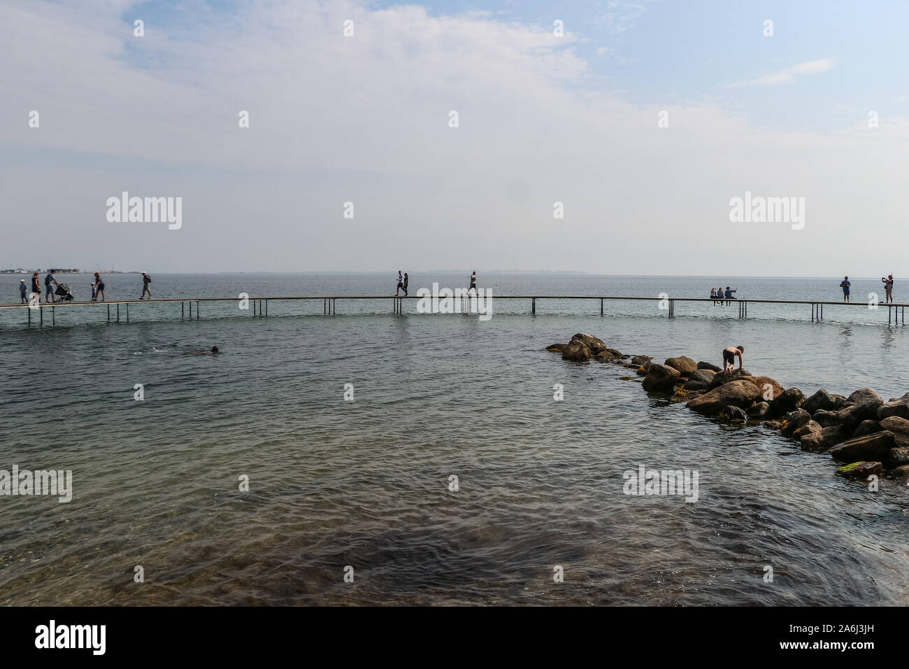 La gente caminando por el puente infinito (Den Uendelige Bro) - muelle de madera con forma de círculo construido sobre un mar de la costa de la Bahía de Aarhus sobre una playa de Varna/Ballehage Playa, creado por el arquitecto Niels Povlsgaard y Johan Gjødes son vistos en Aarhus, Dinamarca, el 30 de julio de 2019 © Michal Fludra / Alamy Live News Foto de stock
