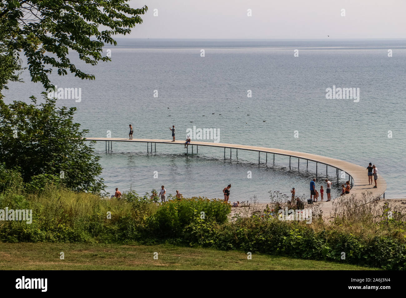 La gente caminando por el puente infinito (Den Uendelige Bro) - muelle de madera con forma de círculo construido sobre un mar de la costa de la Bahía de Aarhus sobre una playa de Varna/Ballehage Playa, creado por el arquitecto Niels Povlsgaard y Johan Gjødes son vistos en Aarhus, Dinamarca, el 30 de julio de 2019 © Michal Fludra / Alamy Live News Foto de stock