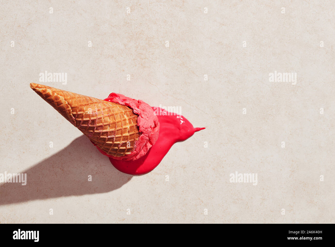 Helado de fresa con cono de waffle cayó en el piso y de la fusión en el suelo bajo la luz caliente del verano. Plana Vista laicos Foto de stock