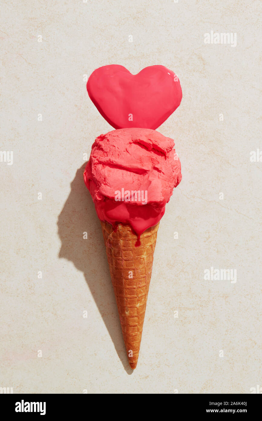 Helado de fresa con cono de waffle derritiendo en el suelo en forma de corazón de amor. El amor de helados Foto de stock