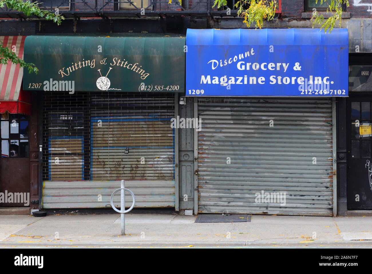 Dos escaparates cerrados y cerrados con dos puertas de seguridad de estilo diferente en el barrio Upper East Side de Manhattan en la ciudad de Nueva York Foto de stock