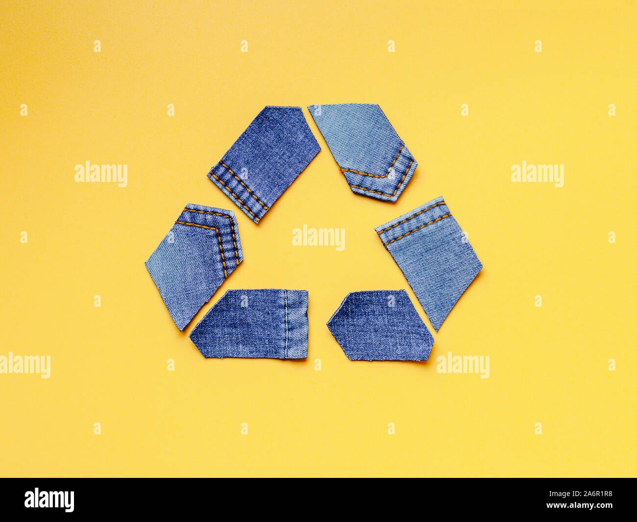 Reducir, reutilizar, reciclar el concepto de fondo. Símbolo de reciclado de viejos jeans sobre fondo amarillo. Vista superior plana o de laicos. Foto de stock