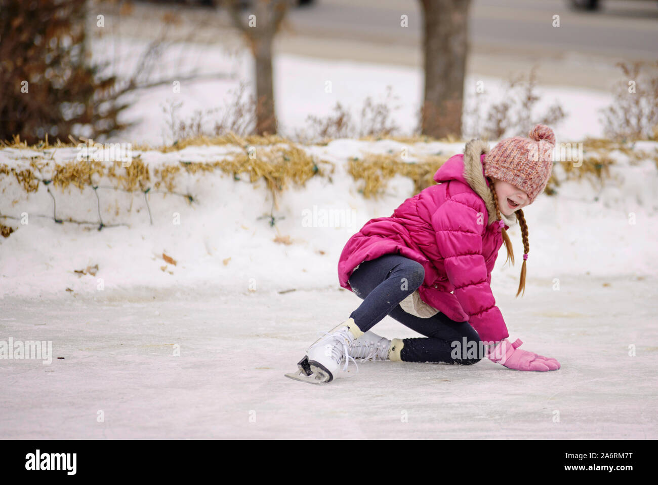 Niña cayendo mientras que el patinaje sobre hielo Foto de stock