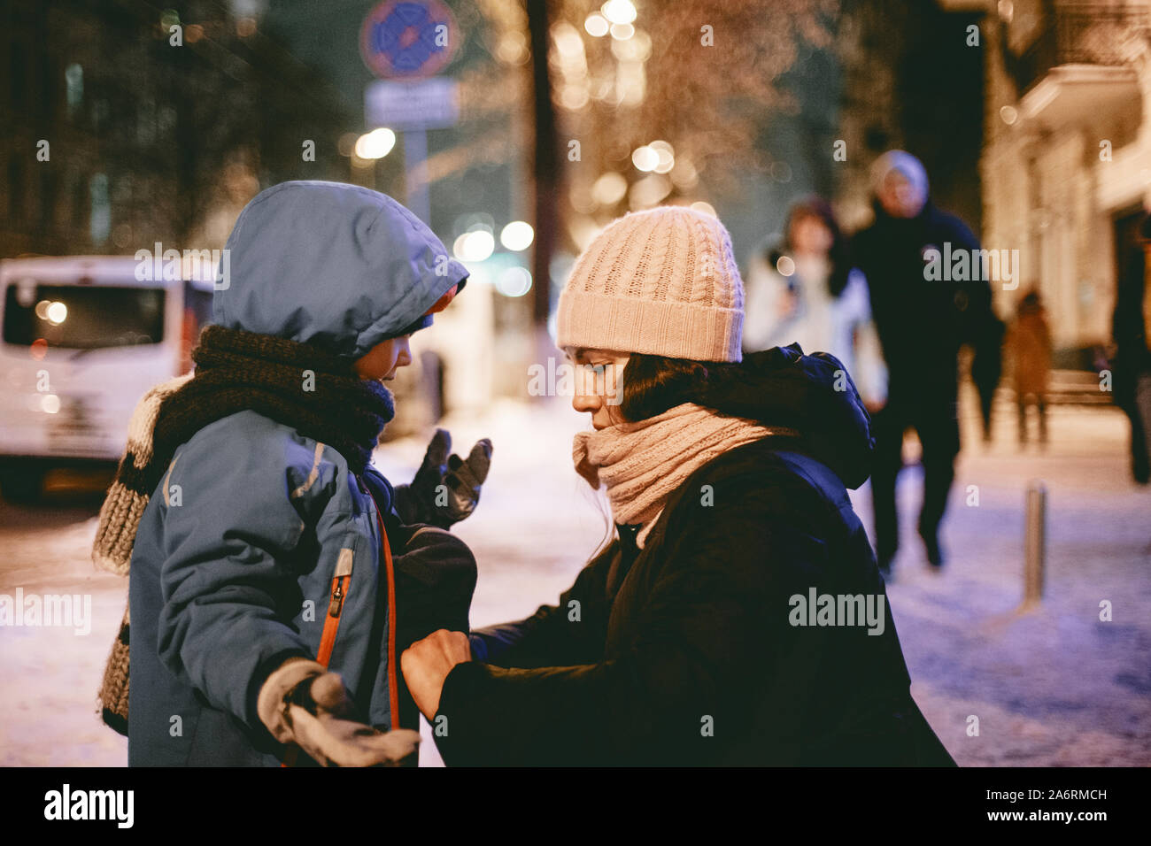 Madre comunicando con el hijo mientras surcan su chaqueta en calle Foto de stock