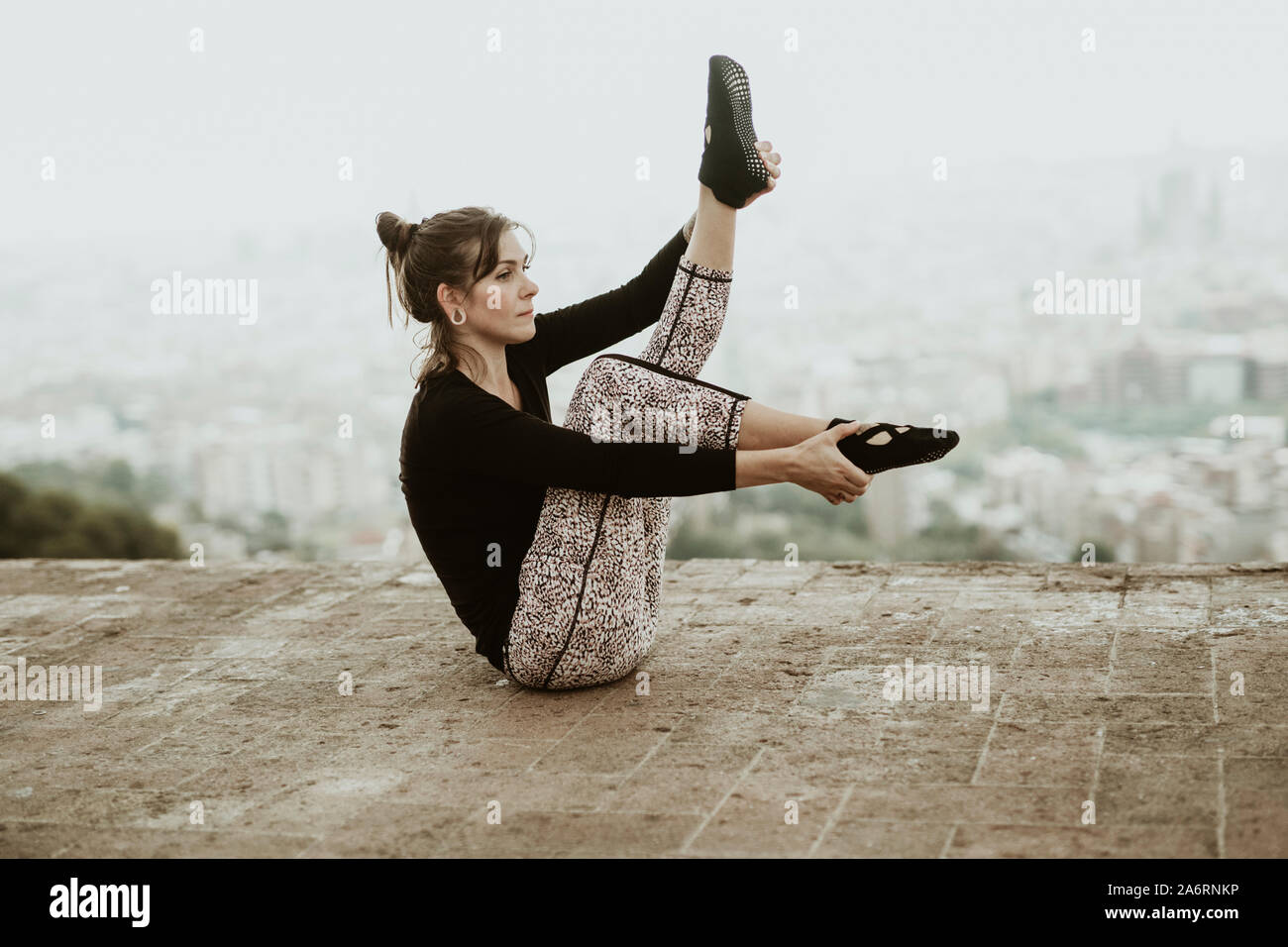 Mujer joven practicando yoga, asana sosteniendo sus pies con sus manos Foto de stock
