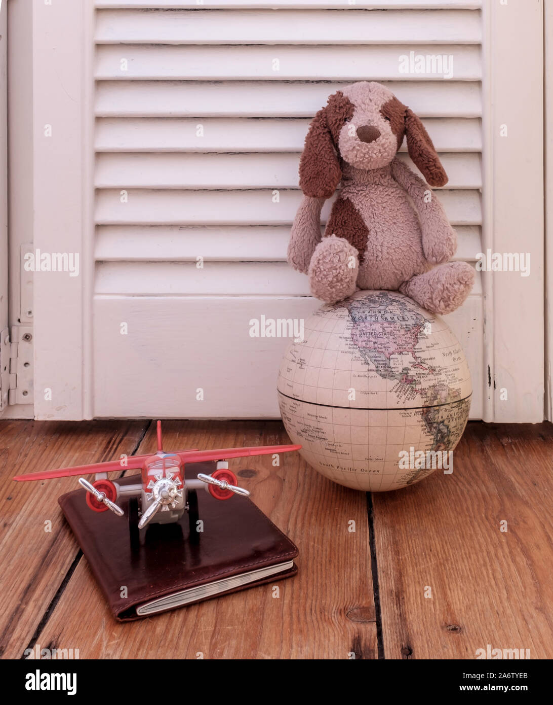 Concepto de viaje para niños, mostrando un peluche sobre una vintage globo con pasaporte y plano. Foto de stock