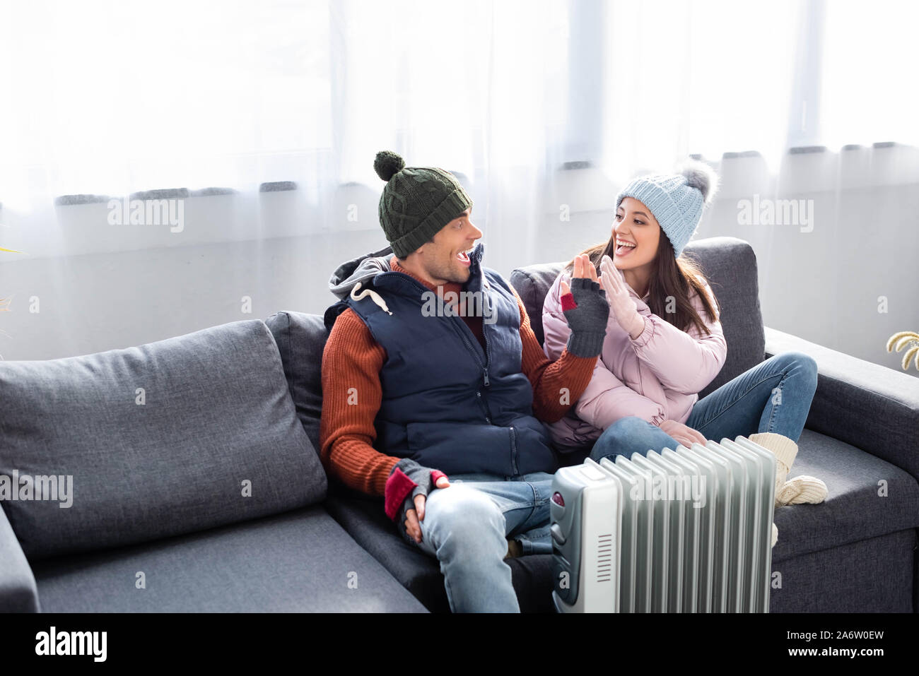 Atractiva novia y novio en traje de invierno calentando cerca del  calefactor y dando alta cinco Fotografía de stock - Alamy