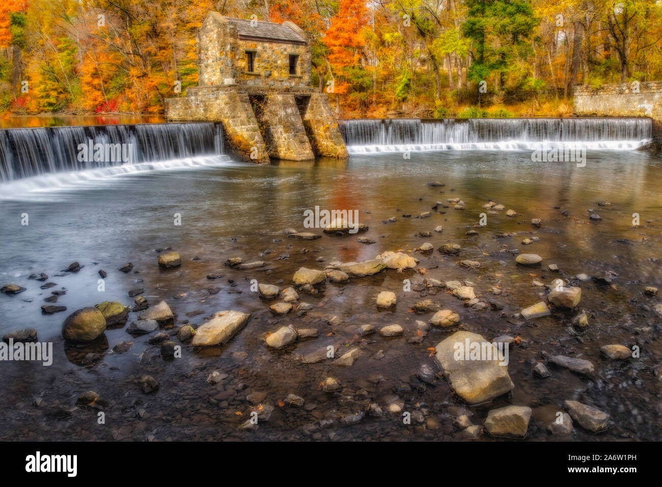 Speedwell Presa y cascada - Vistas a la estructura de piedra sobre el río Whippany rodeado por los cálidos colores del follaje de otoño. Foto de stock