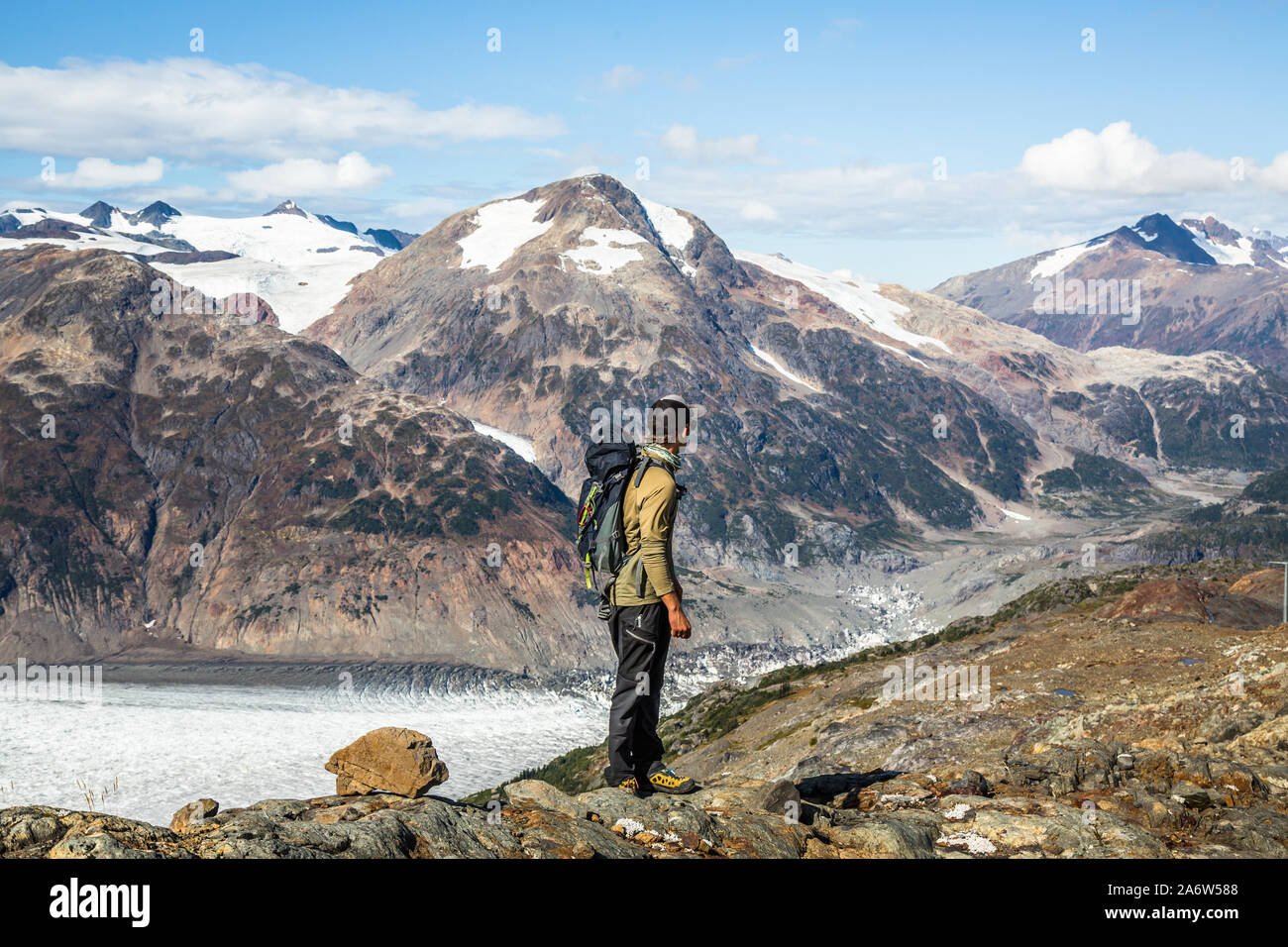 Hombre senderismo a través de la Canadian travesía mirando a lo largo de los escarpados picos y glaciares, cerca de la frontera de la Columbia Británica y Alaska. Foto de stock