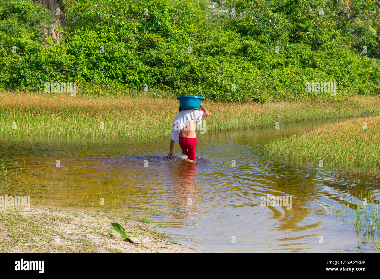 El hombre que estaba lavando ropa en el río llevando sobre sus hombros una  cuchara en la aldea hippie de Arembepe, Brasil Fotografía de stock - Alamy