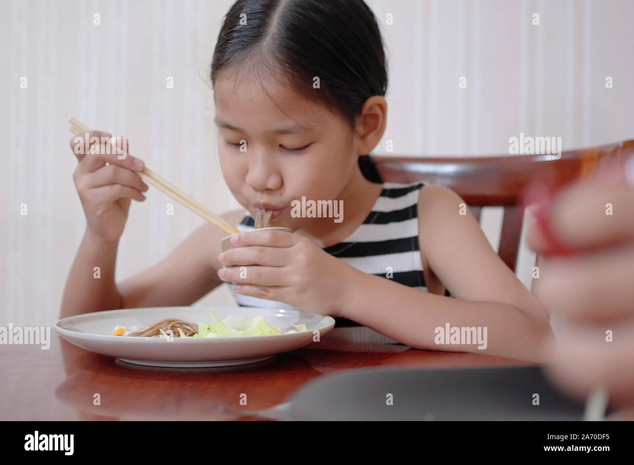 Una muchacha comiendo fideos de trigo sarraceno Foto de stock