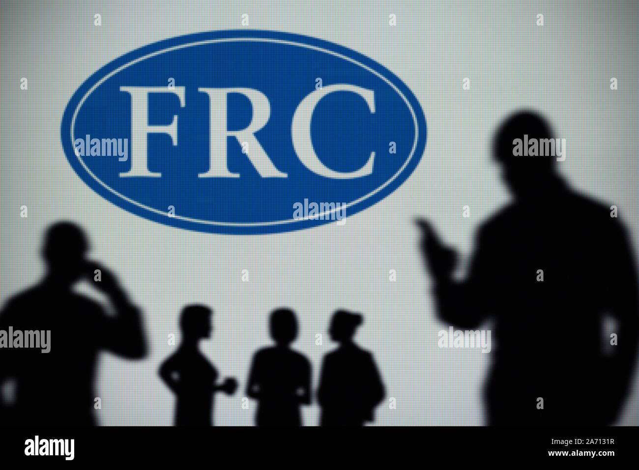 El FRC (Consejo de Informes Financieros logo es visto en una pantalla LED en el fondo mientras una silueta persona utiliza un smartphone (uso Editorial solamente) Foto de stock