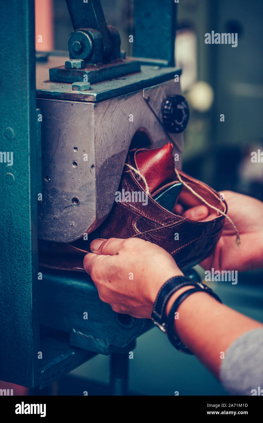 Manos de un experimentado trabajador puso el zapato en una máquina de moldeo de zapata especial Foto de stock