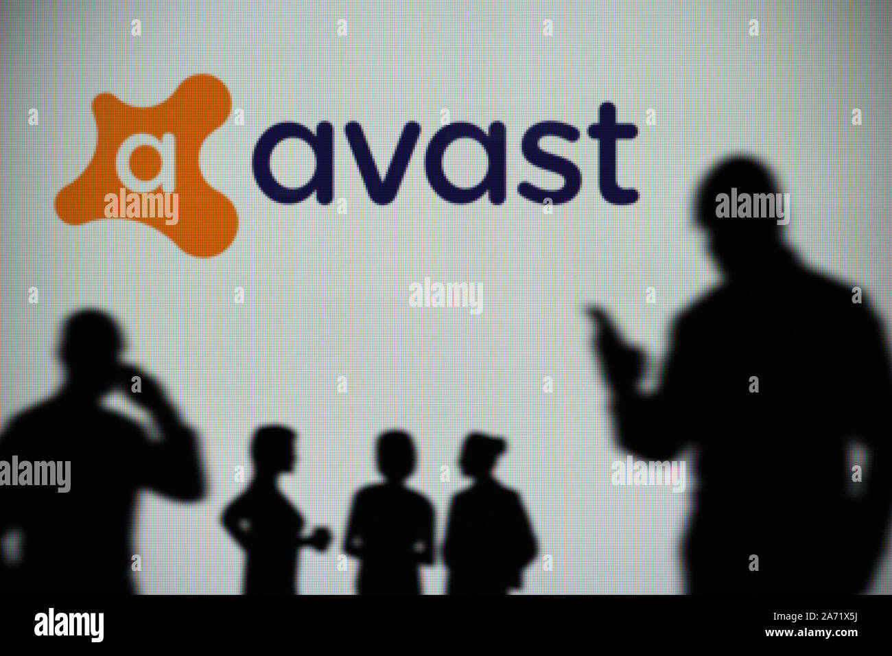 El logotipo de Avast es visto en una pantalla LED en el fondo mientras una silueta persona utiliza un smartphone (uso Editorial solamente) Foto de stock