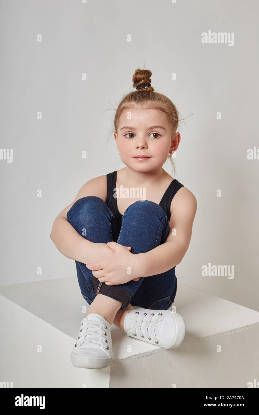 Chica con el cabello largo de moda en ropa casual sentado en un cubo blanco  y posando. Hermosa niña. Rusia, Sverdlovsk, 4 de febrero de 2018 Fotografía  de stock - Alamy