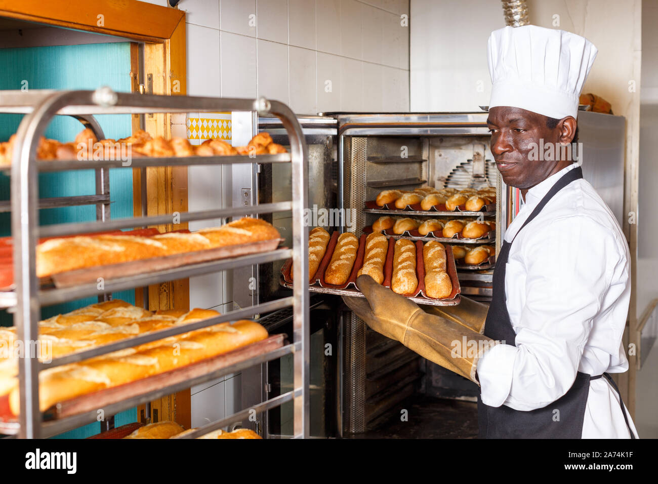 Baker experimentados que trabajan en la pequeña panadería, sacar el pan del  horno industrial y poner en rack Fotografía de stock - Alamy