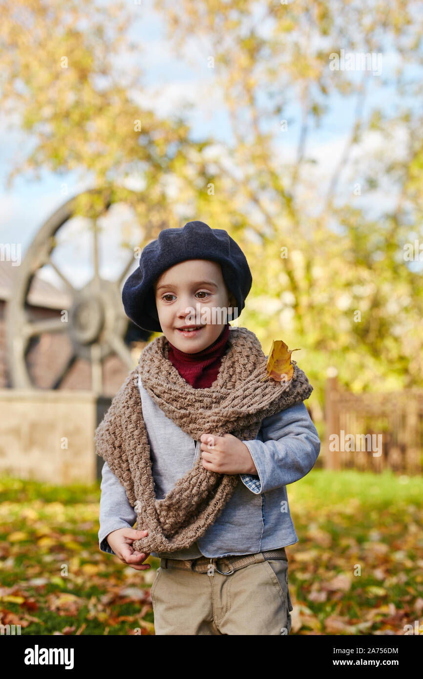 Los niños bebé en otoño retro ropa de primavera. La pequeña niña sentada  sonriente en la naturaleza, la bufanda alrededor de su cuello, clima  fresco. Emociones brillante en su rostro. Rus Fotografía