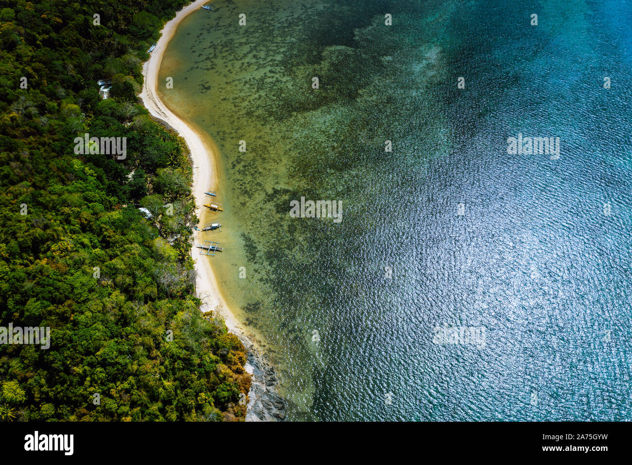 En Palawan, Filipinas, El Nido. Antena drone vista anterior de una apartada playa desierta con embarcaciones tradicionales locales en costa delante de Foto de stock