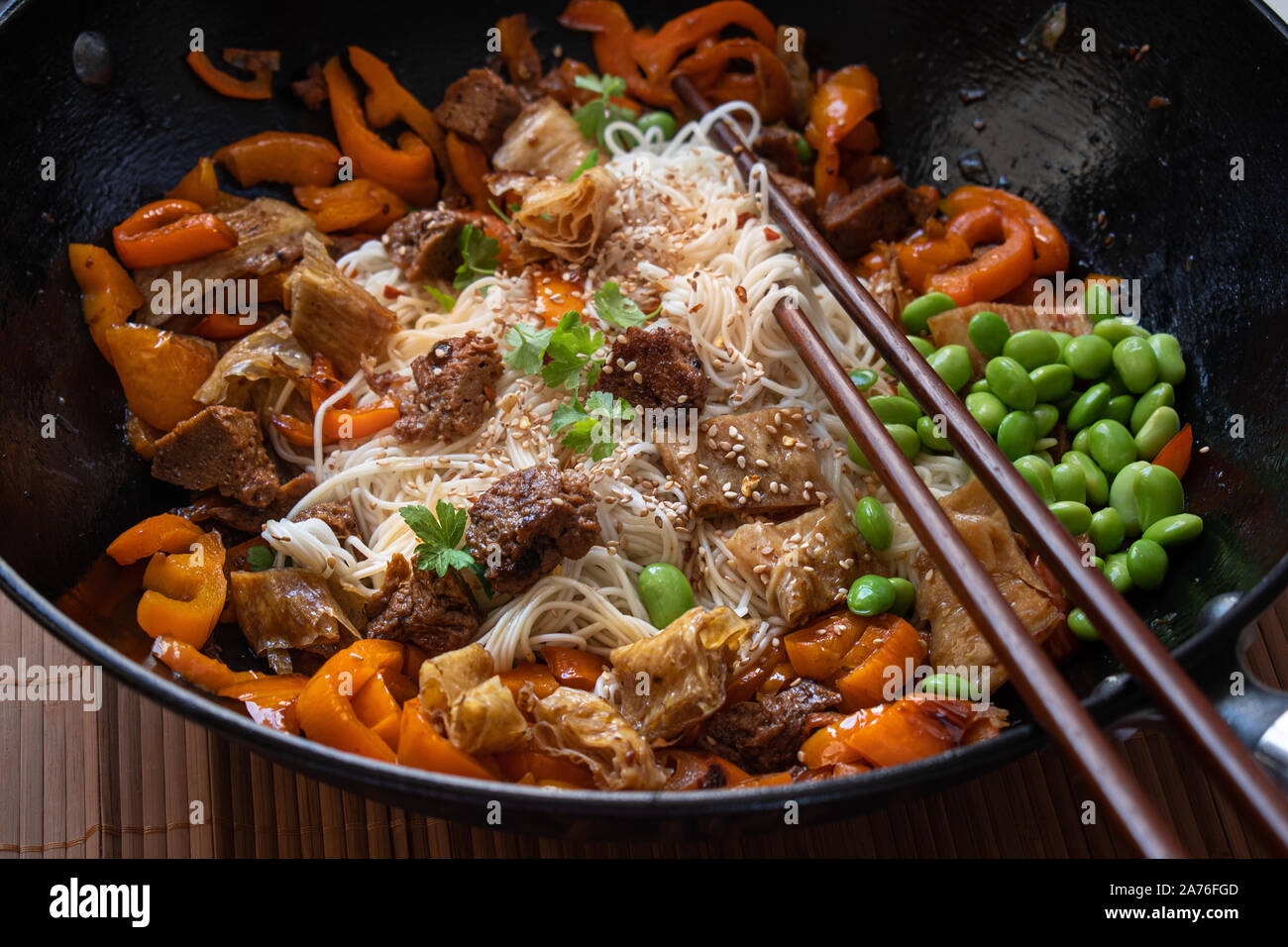 Vegan salteado con yuba, seitán, pimiento, edamame. Los fideos de trigo,  servido en el wok Fotografía de stock - Alamy