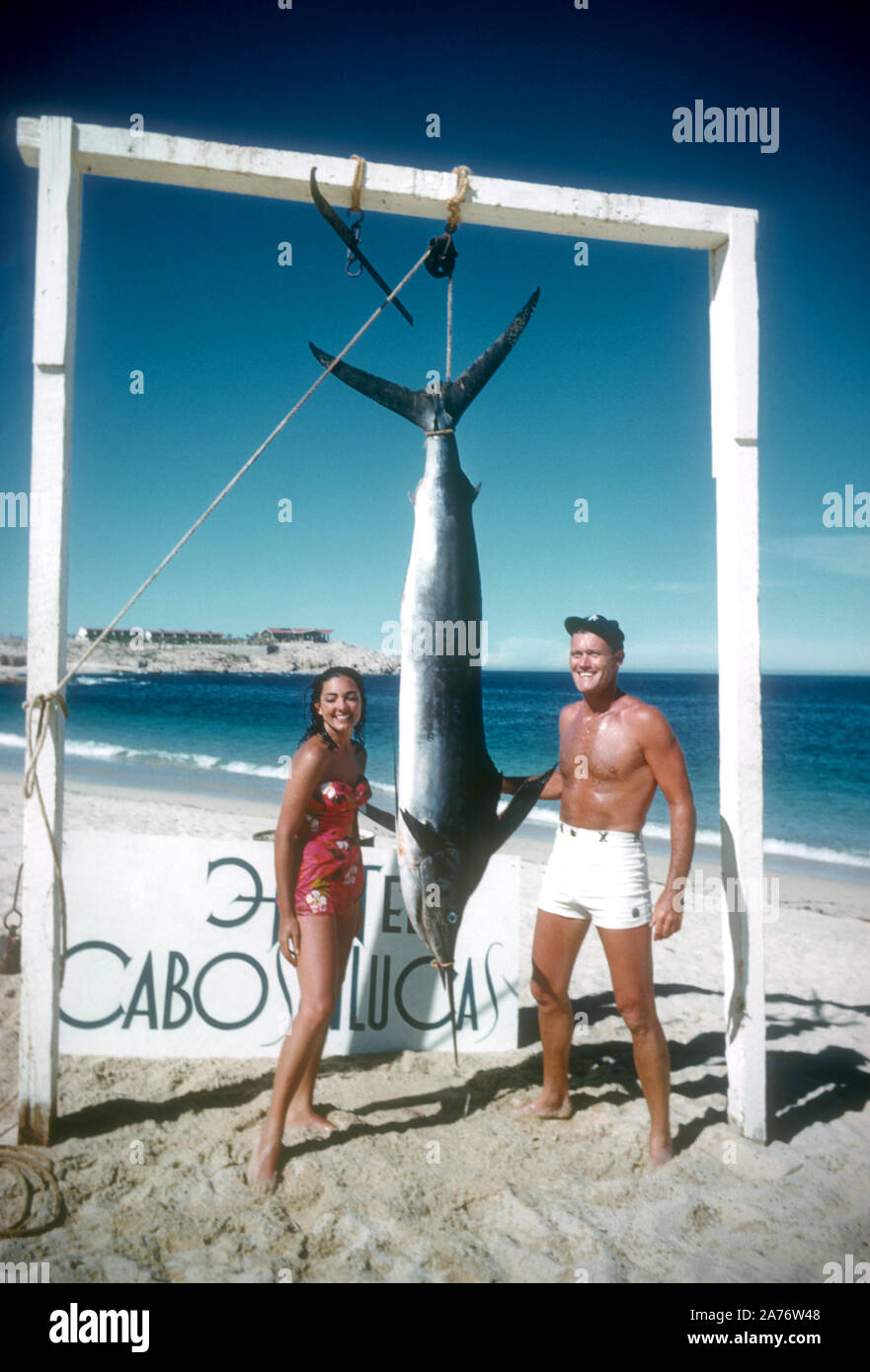 BAJA CALIFORNIA, MÉXICO - JUNIO DE 1962: el actor y ex jugador de béisbol Chuck Connors (1921-1992) y la actriz prometido Kamala Devi (1934-2010), posan para una fotografía delante de un marlin que Connors capturado mientras estaba en un viaje de pesca alrededor de junio de 1962, en Baja California, México. (Foto por Hy Peskin) (número de registro: X8569) Foto de stock