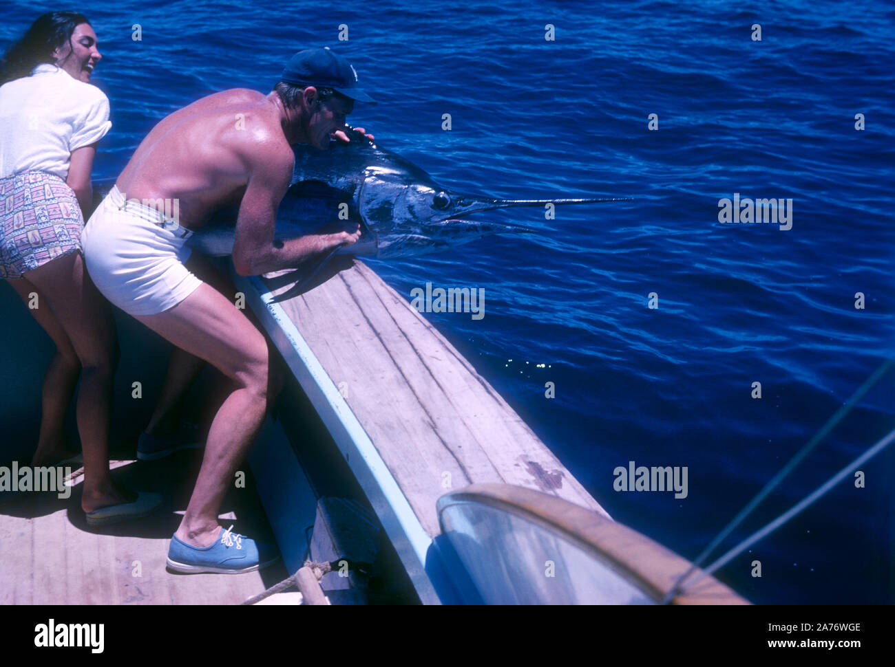 BAJA CALIFORNIA, MÉXICO - JUNIO DE 1962: el actor y ex jugador de béisbol Chuck Connors (1921-1992) y la actriz prometido Kamala Devi (1934-2010) tirar un marlin en el barco mientras estaba en un viaje de pesca alrededor de junio de 1962, en Baja California, México. (Foto por Hy Peskin) (número de registro: X8569) Foto de stock
