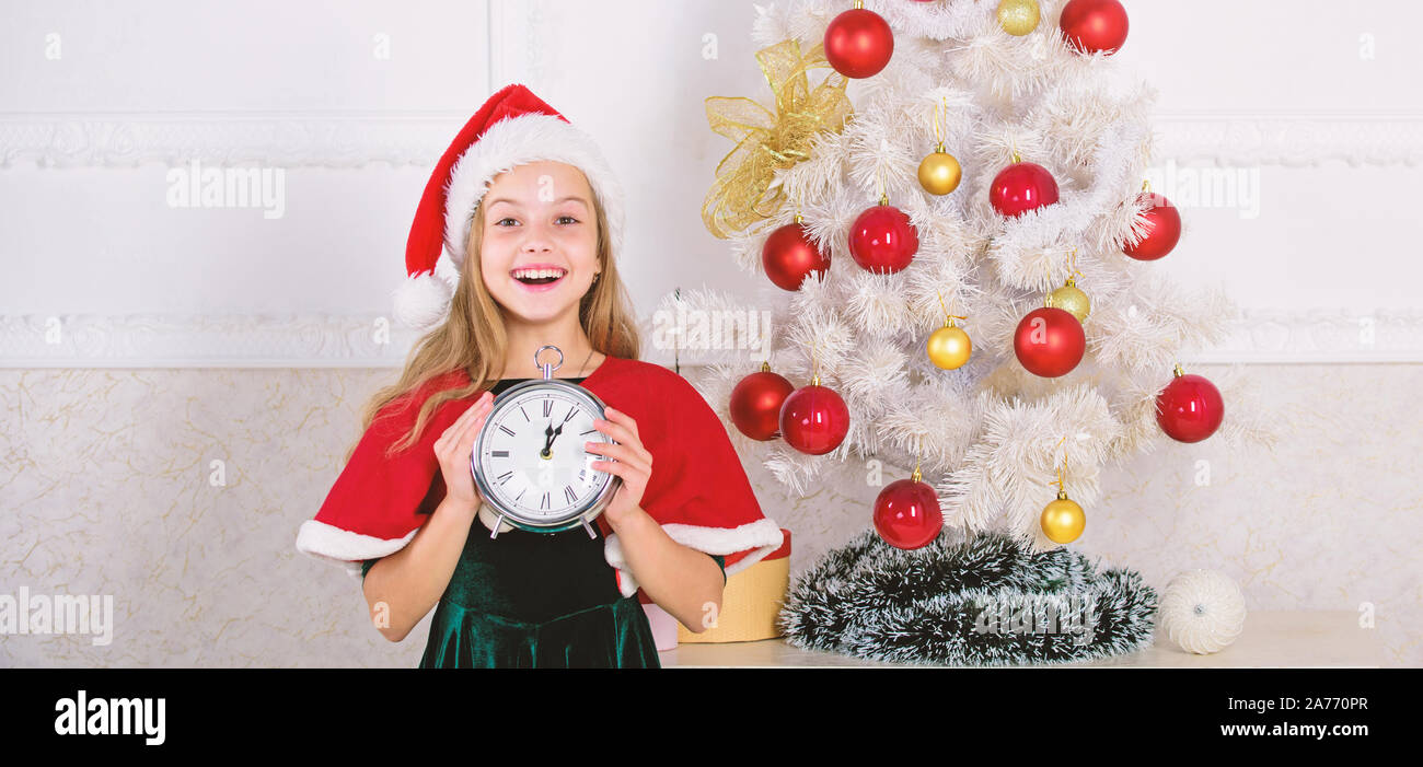 Cuenta regresiva de año nuevo. Chica kid disfraz gorro de Papá Noel con  reloj entusiasmado cara feliz el conteo del tiempo para el año nuevo.  Último minuto hasta la medianoche. Último minuto