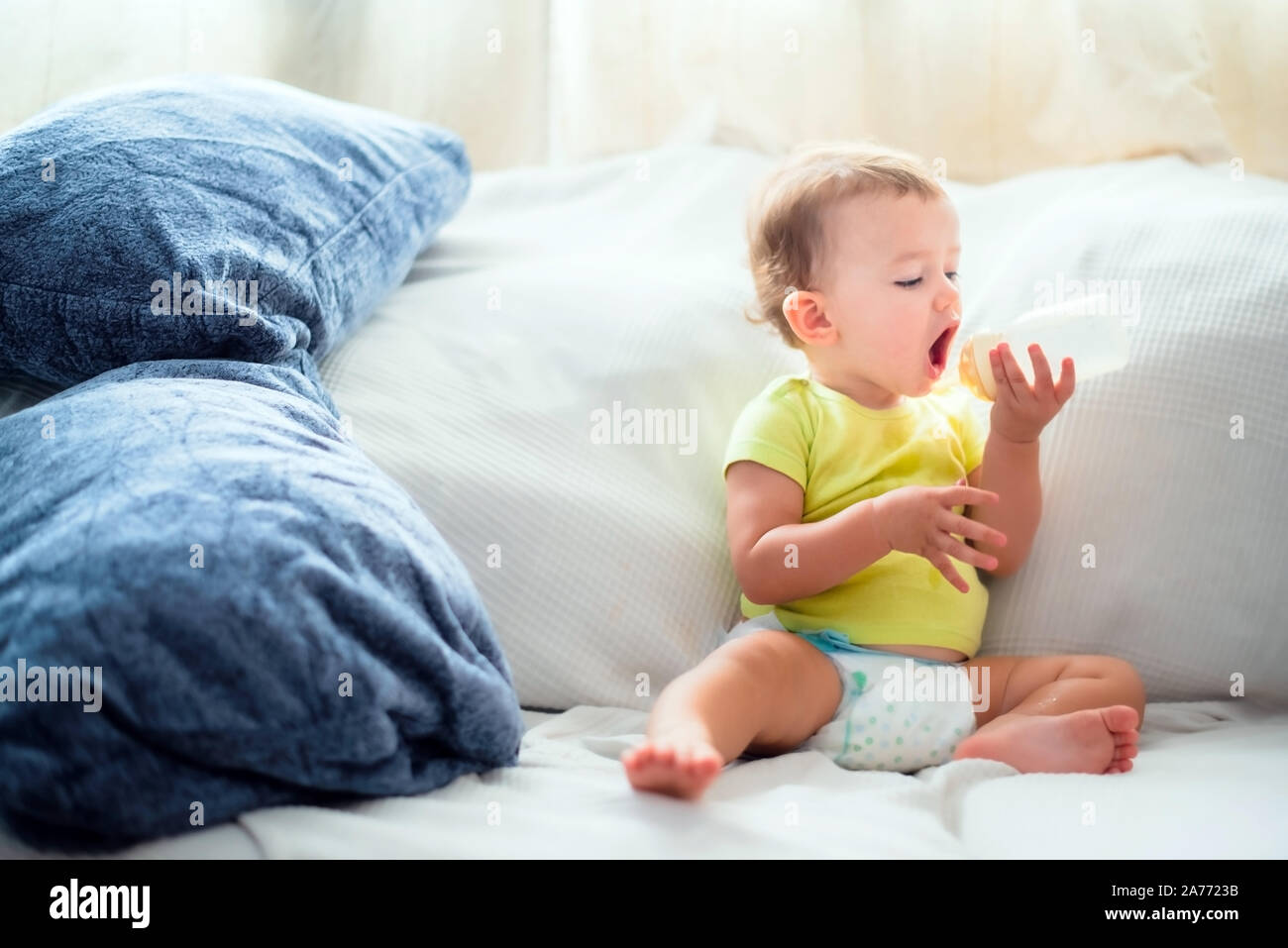 Bebé tomando su biberón de leche en un sofá con un gracioso y hambriento de  expresión Fotografía de stock - Alamy