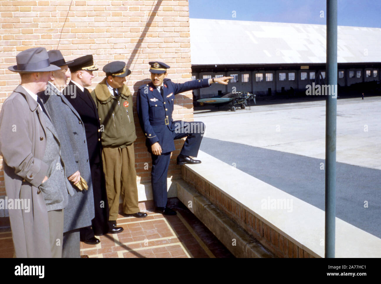 1954: un miembro de las fuerzas armadas habla con otros miembros de las fuerzas armadas en un aeródromo en 1954. (Foto por Hy Peskin) Foto de stock