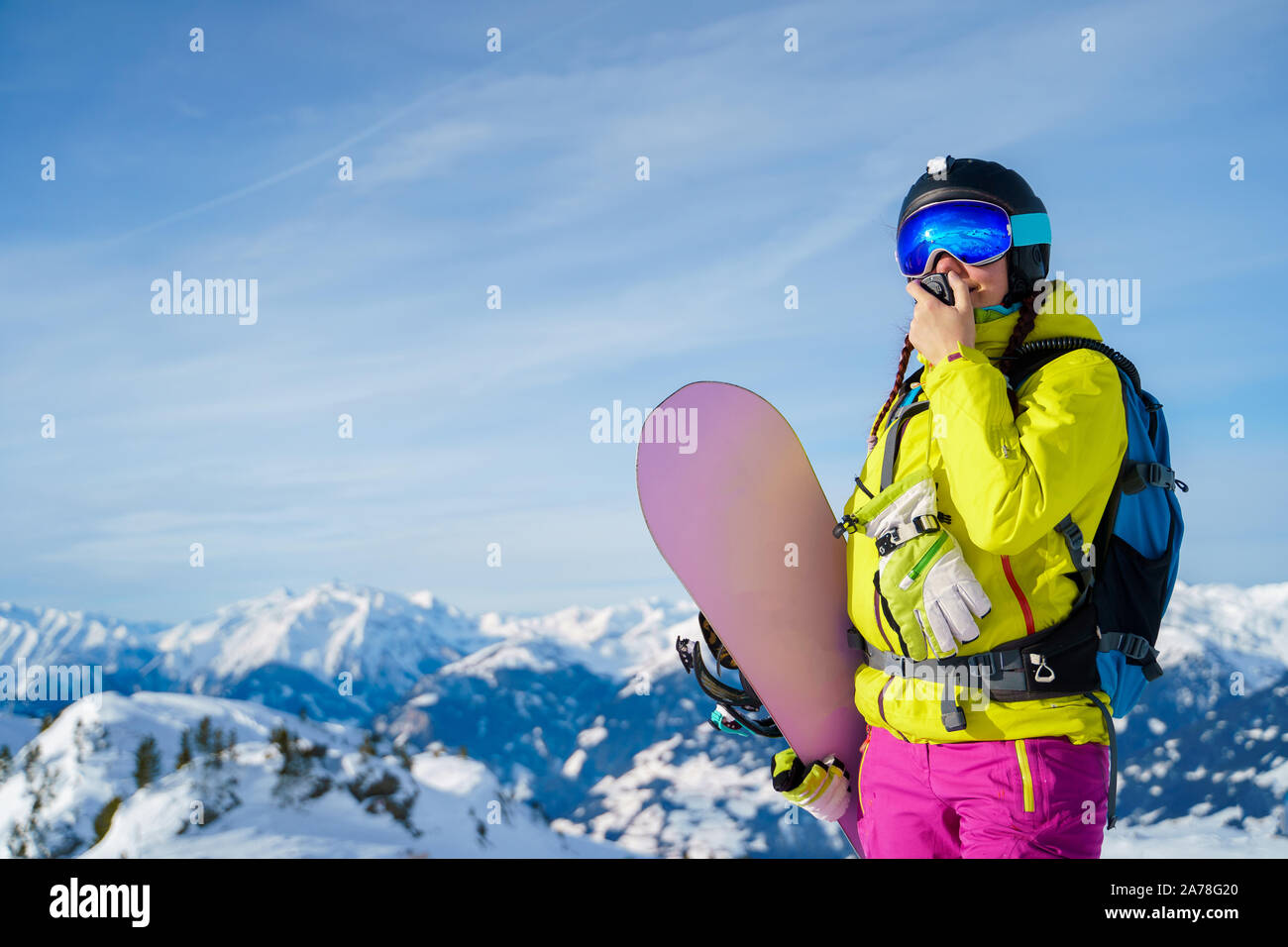 Foto de mujer en casco y con snowboard hablando por walkie-talkie de pie al  ski resort de tarde Fotografía de stock - Alamy
