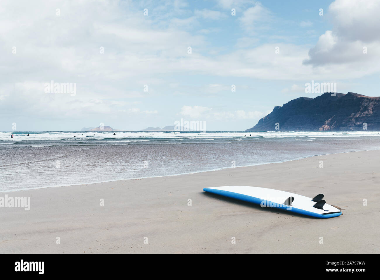 Las tablas de surf boca abajo sobre una amplia playa arenosa contra el mar y las montañas en día ventoso Foto de stock