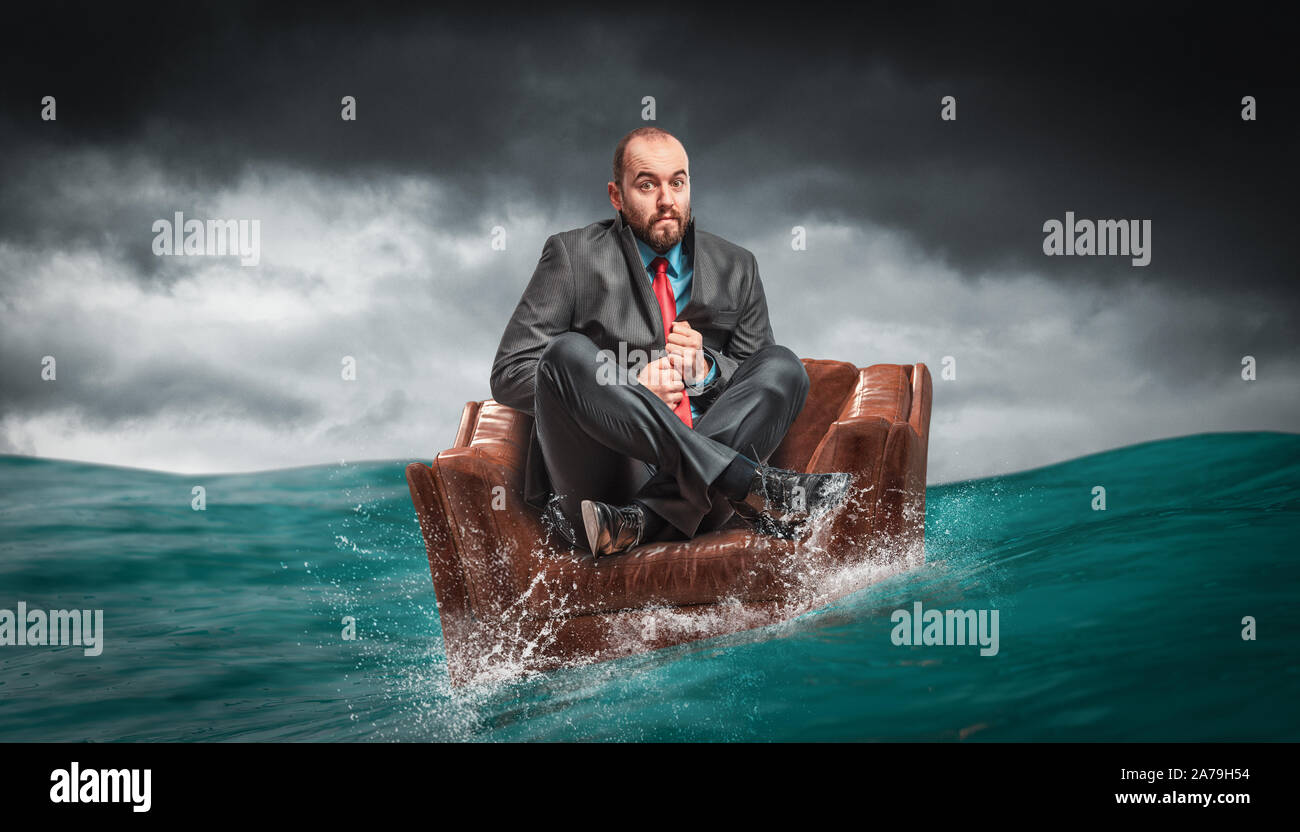 Hombre sentado en un sillón flotando sobre el agua del océano. concepto de crisis y problemas en el trabajo. Foto de stock