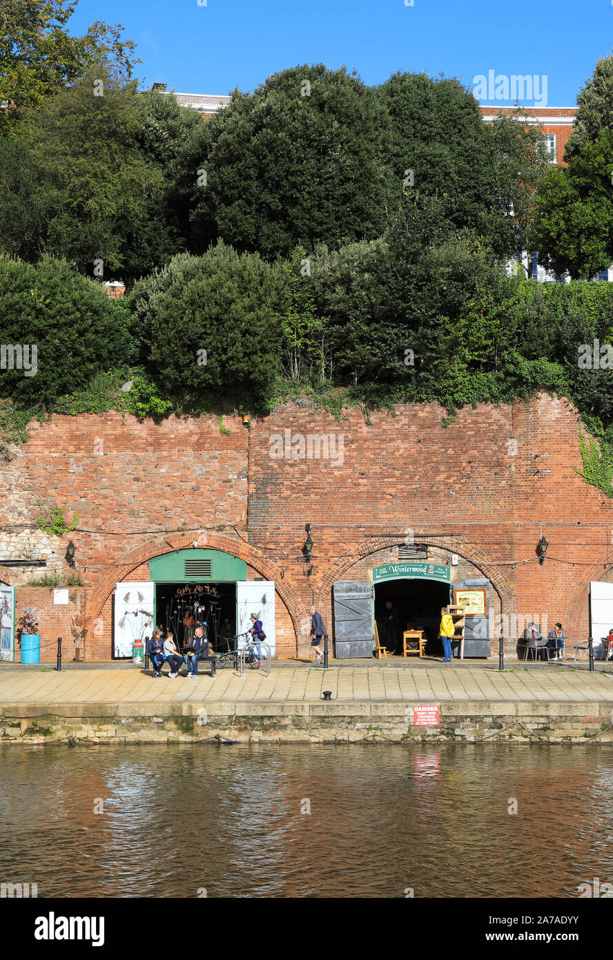 Sol de otoño en las tiendas independientes ahora en los viejos arcos de ladrillo de almacenes del siglo XIX, en la histórica zona de Quayside en Exeter, en Devon, Reino Unido Foto de stock