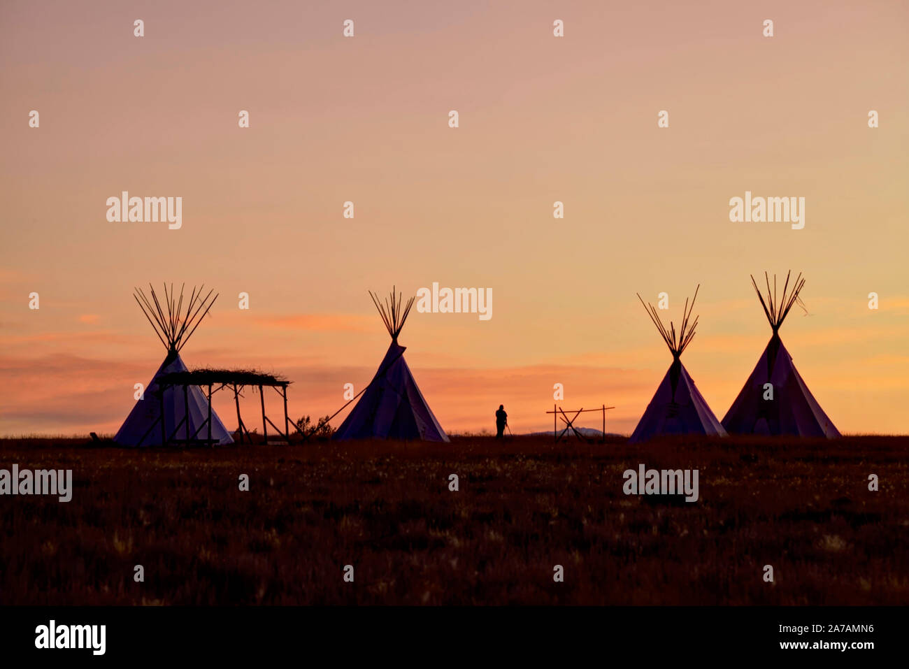Una reproducción de cómo los indios (nativos americanos) utilizar para vivir en la pradera. Un solitario fotógrafo es fotografiar la puesta de sol. Foto de stock