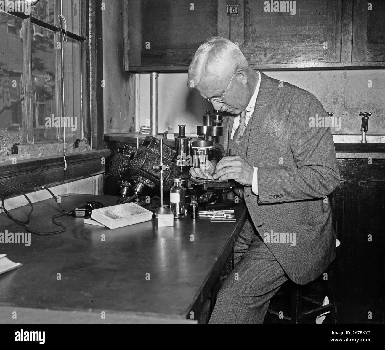 Hombre utilizando microscopio en laboratorio ca. 1936 Foto de stock