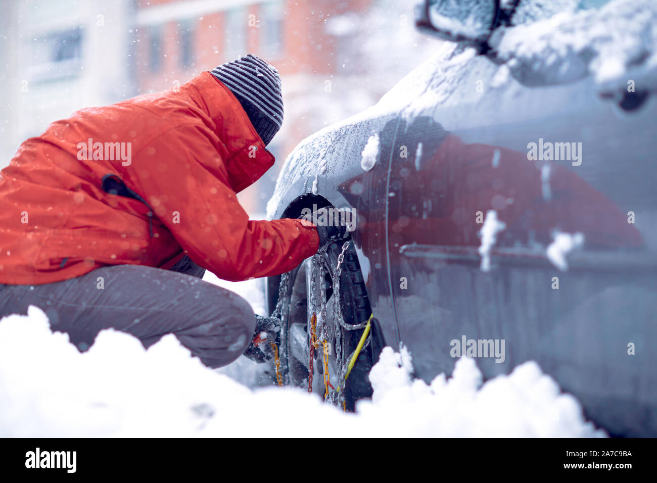 Cadenas para nieve en las ruedas del coche.Man preparando el coche para viajar en invierno día de nieve. Foto de stock