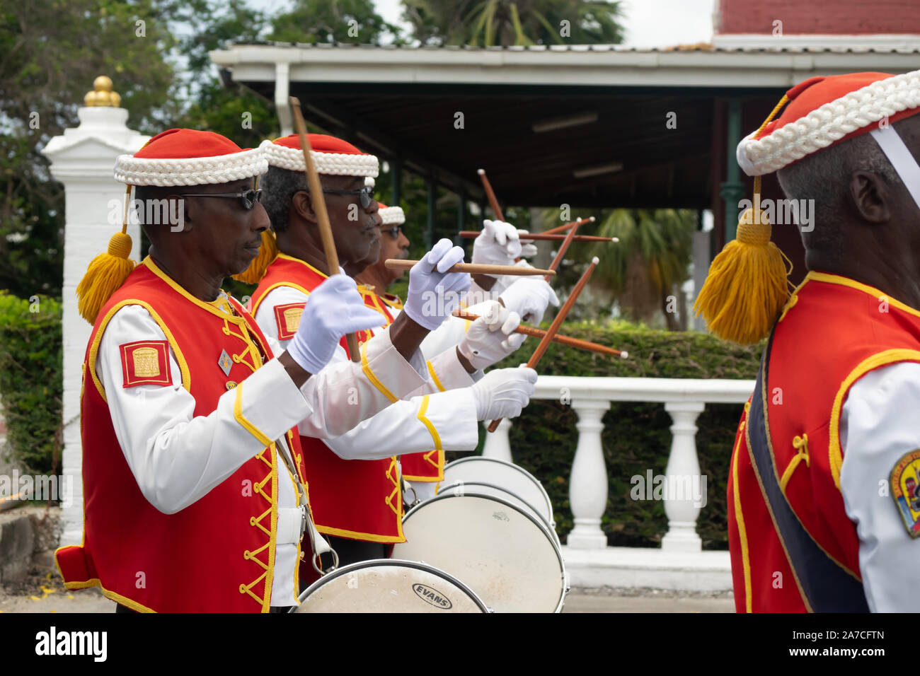 Isla de Barbados el cambio de guardia en la histórica Garrison Savannah. Una fila de tamborileros en rojo uniforme y baquetas en el aire Foto de stock